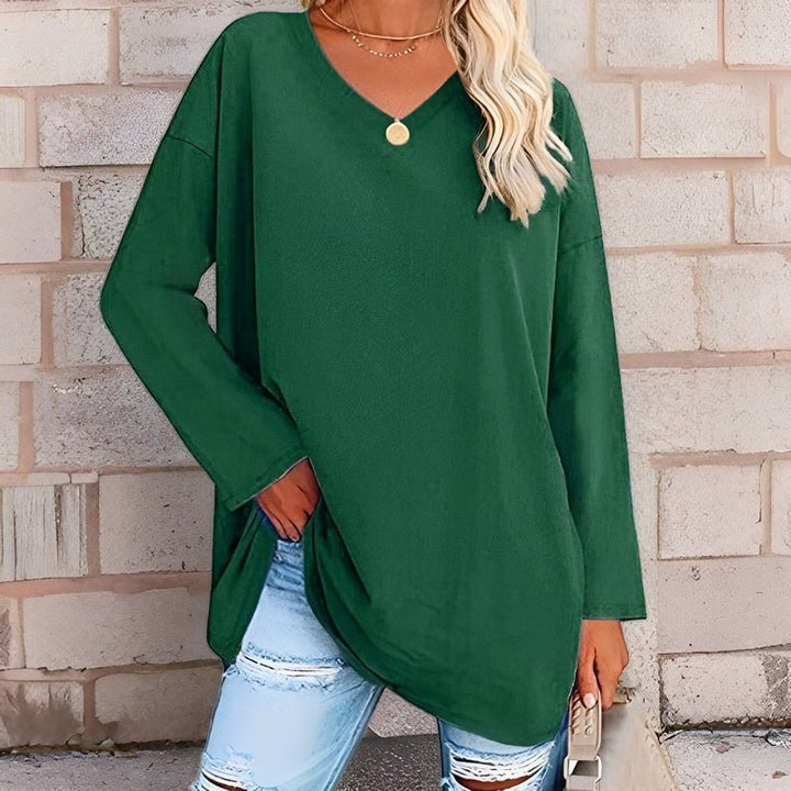 Frau trägt grünes Langarmshirt mit V-Ausschnitt und eine Hand in der Tasche
