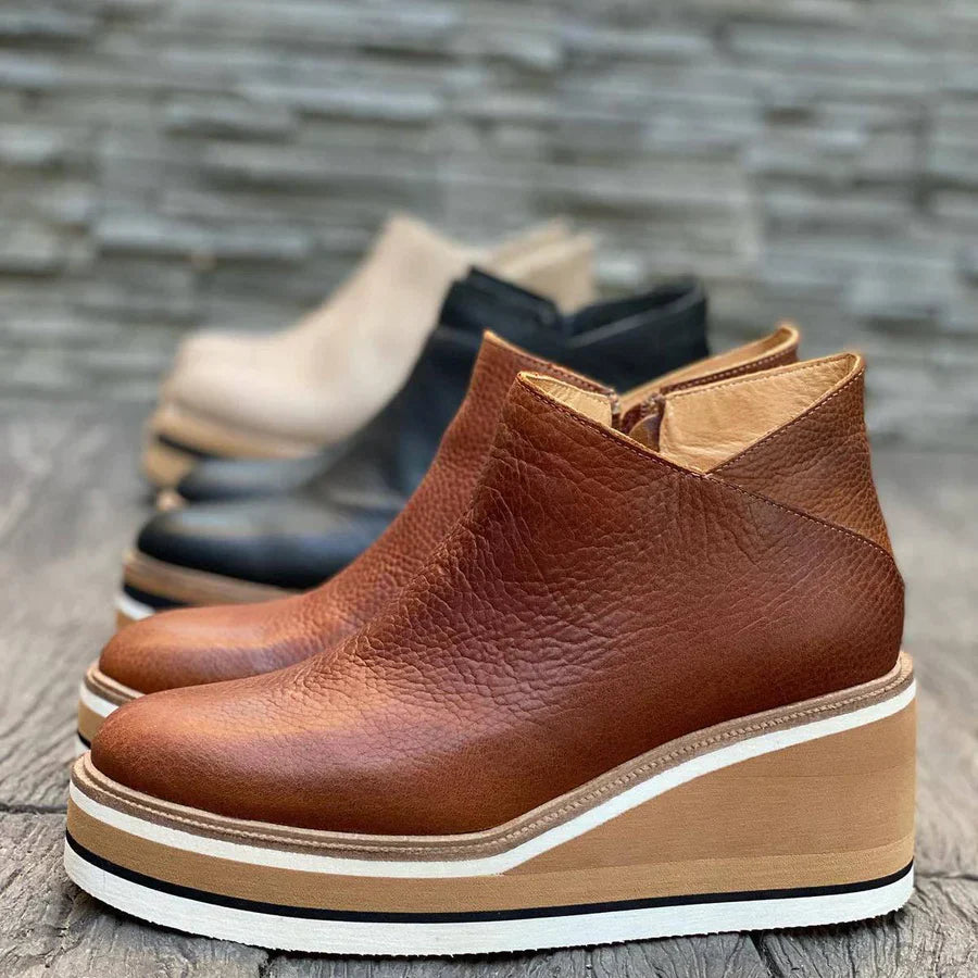 Nahaufnahme von braunen orthopädischen Stiefeletten im Vordergrund, mit leicht verschwommenen Farben anderer Stiefel im Hintergrund.